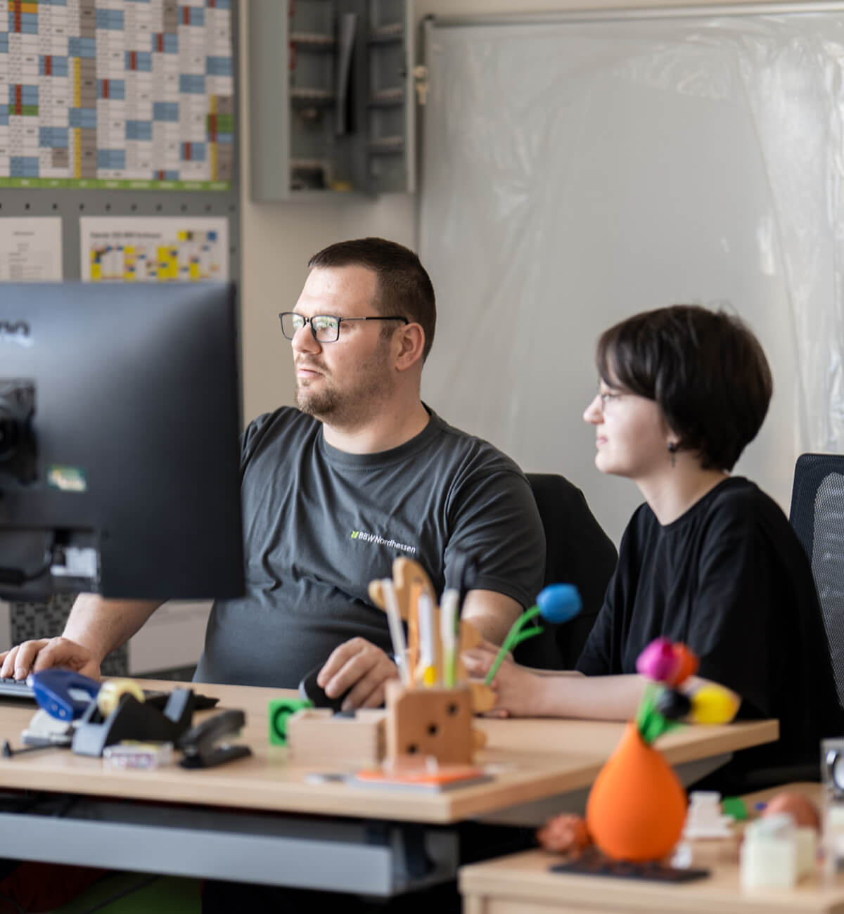 Zwei Personen sitzen gemeinsam an einem Tisch vor einem Computer