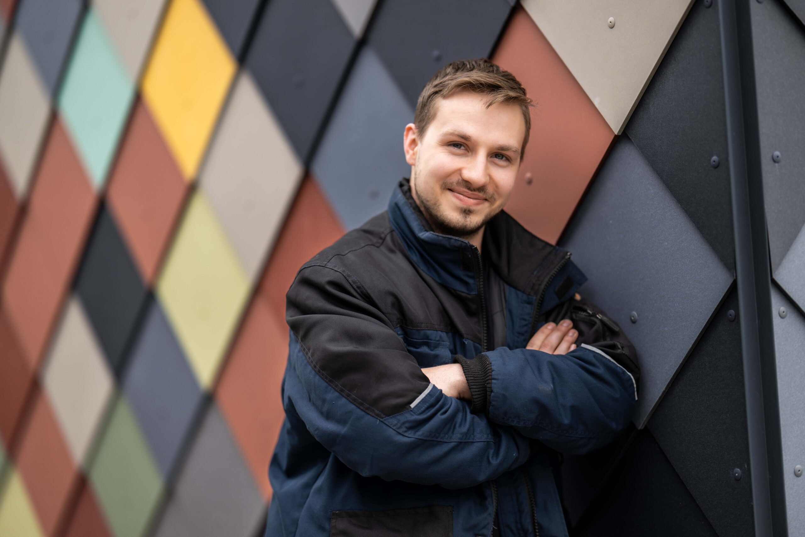 Junge steht lächelnd vor einer bunt gestalteten Fassade